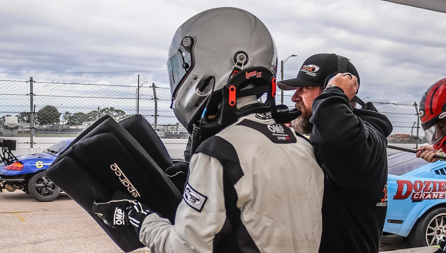 Hayden having his helmet and HANS device adjusted in the pits