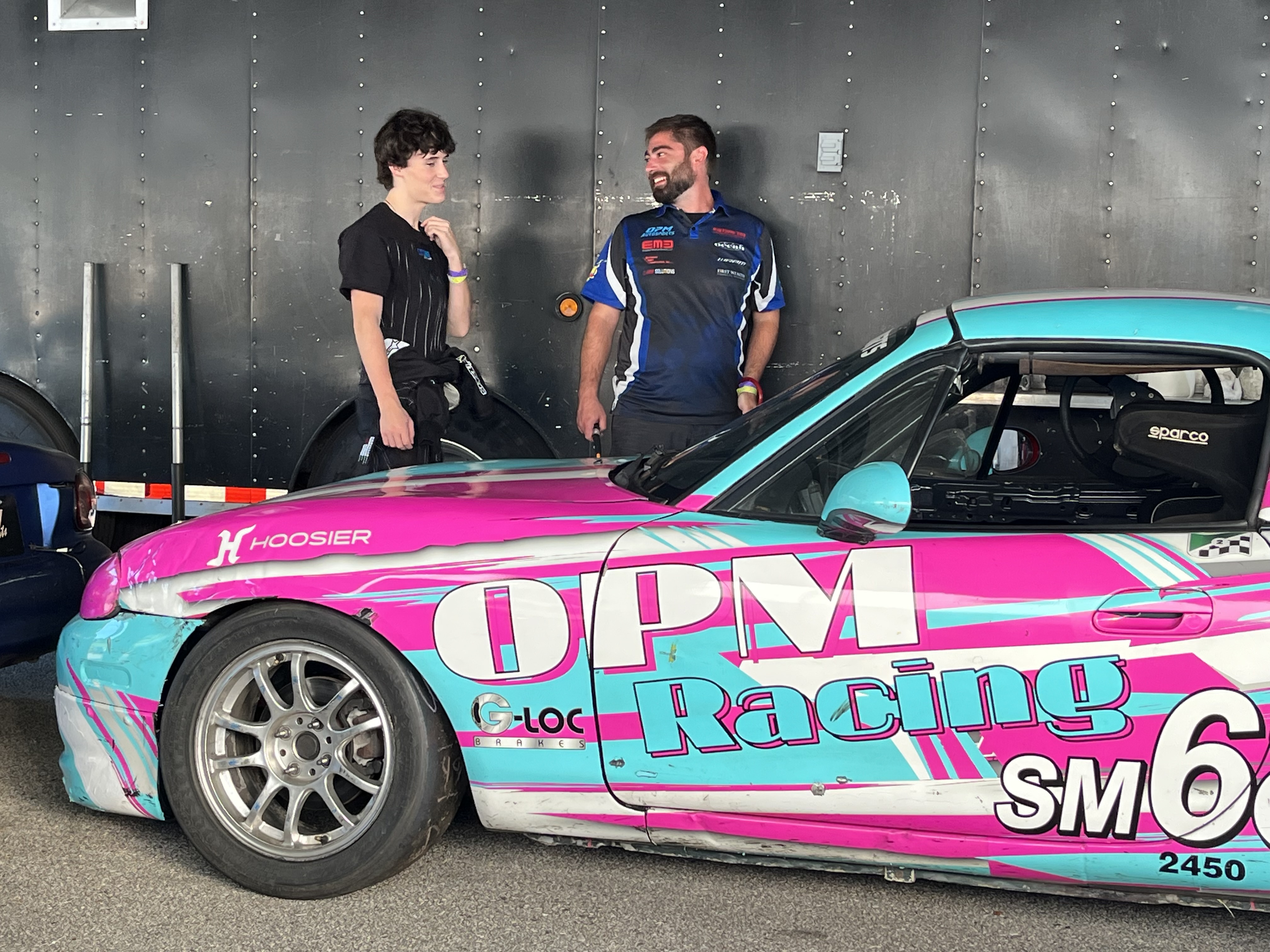 Hayden talking with a teammate next to the OPM Racing Spec Miata