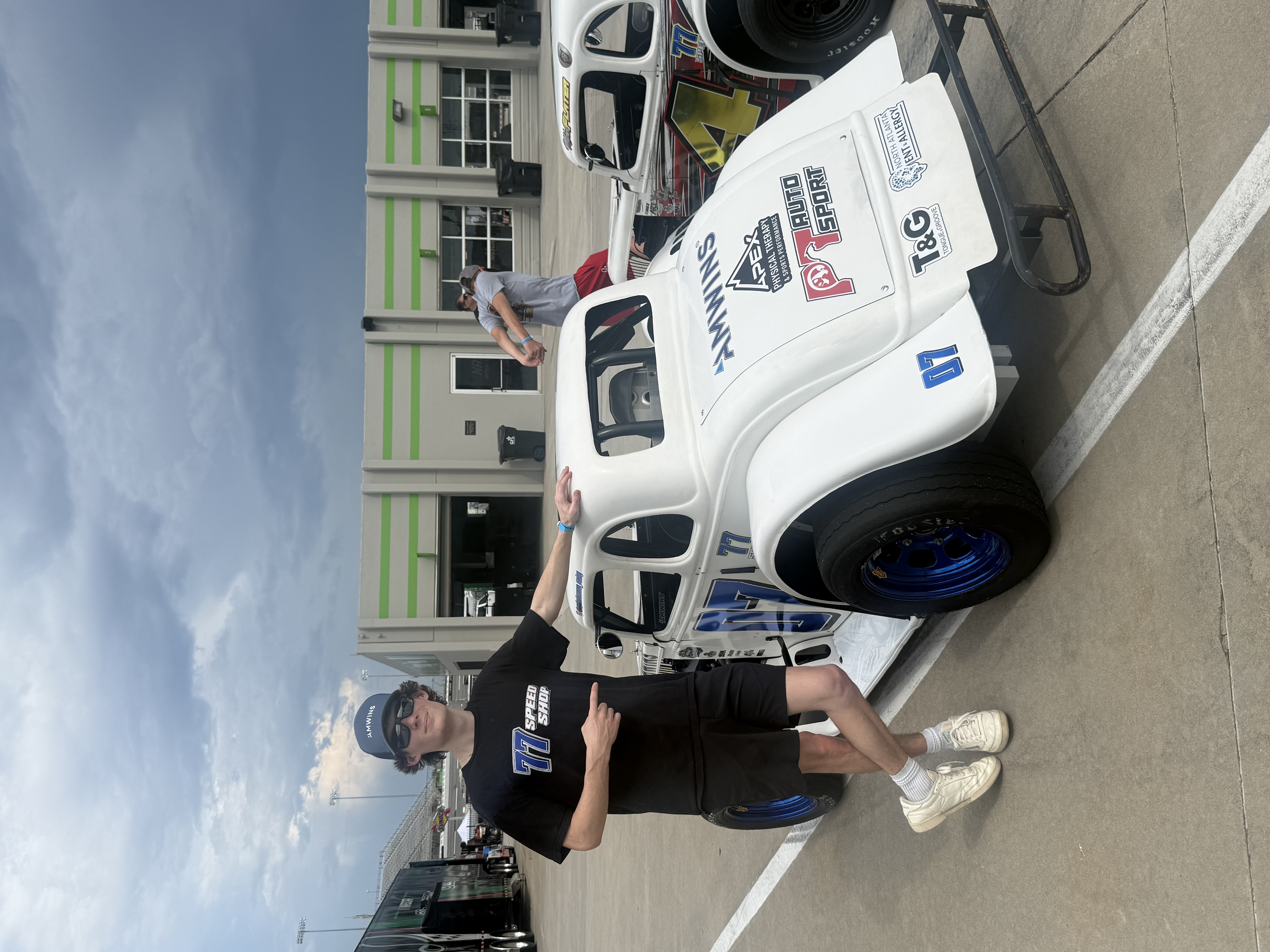 Hayden pointing to his No. 07 77 Speed Shop Legends car showing AMWINS, APEX, PT Auto Sport, T&G, and North Atlanta ENT & Allergy sponsor decals